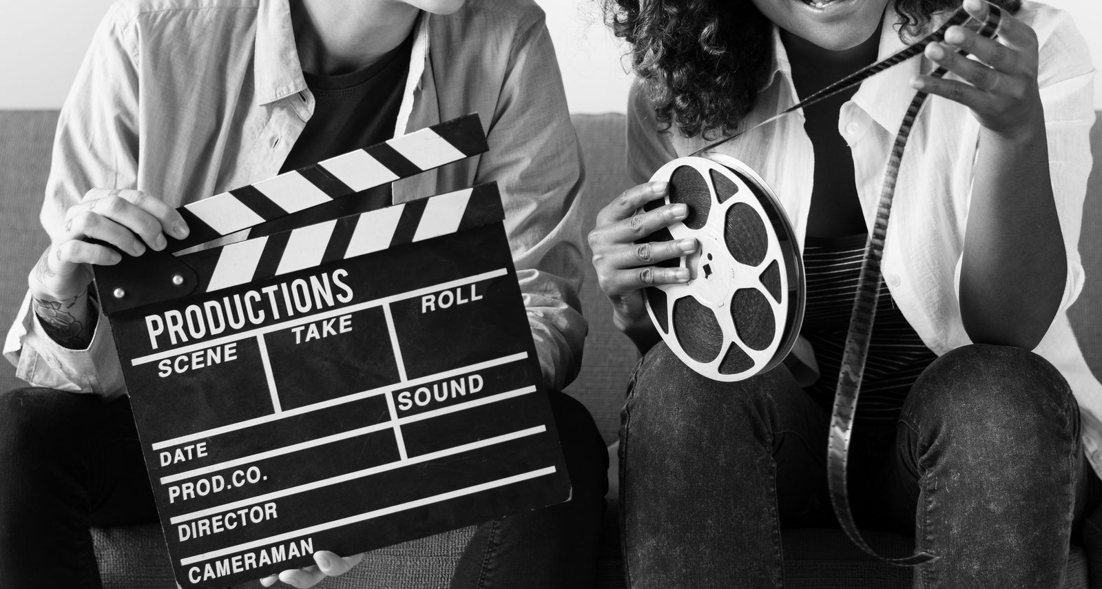 Two people in black and white holding a clapperboard and a film reel